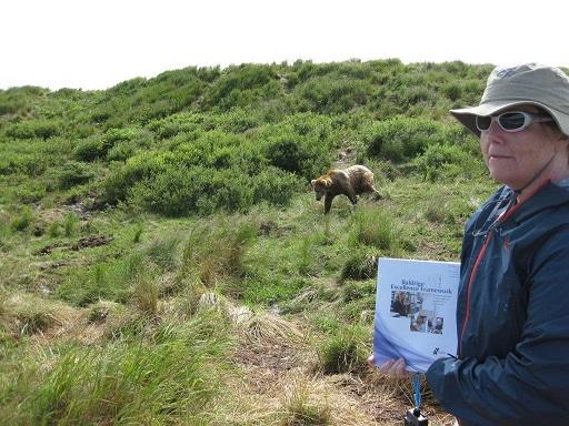 Maureen Washburn holds Baldrige booklet outdoors with a bear in the background