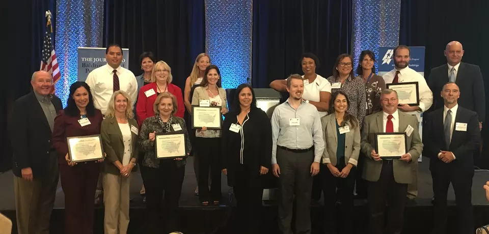 COE 2026 leaders are shown standing for a group photo with awards.