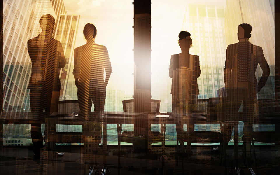 Four people at work in large building looking out at their future in the city skyline.