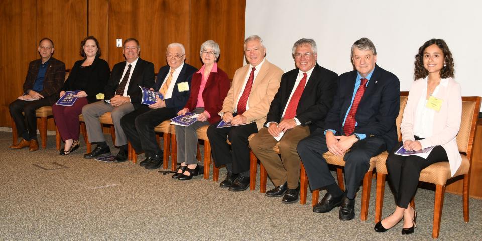 The nine Portrait Gallery inductees sit in a row of chairs.