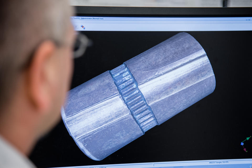 The side of a man's face as he looks at a bullet model on a screen.