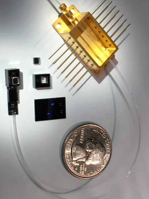 A quarter is shown for scale next to a metal chip and other components.