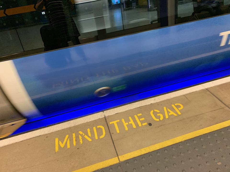 image of a subway train as it rushes past, the words "mind the gap" appear on the subway platform