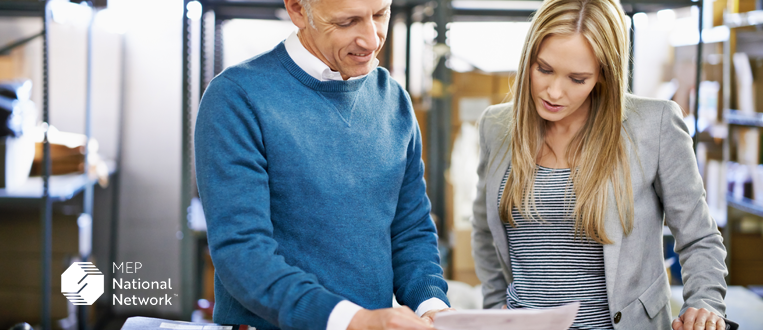 two pepole looking at papers in a manufacturing facility