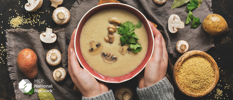 woman in a grey sweater holding a bowl of cream of mushroom soup