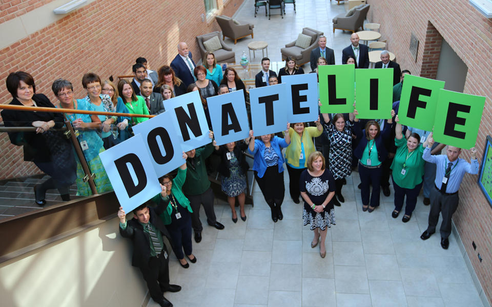 CORE staff celebrates National Blue & Green Day at their headquarters in Pittsburgh, PA by holding up signs spelling Donate Life.