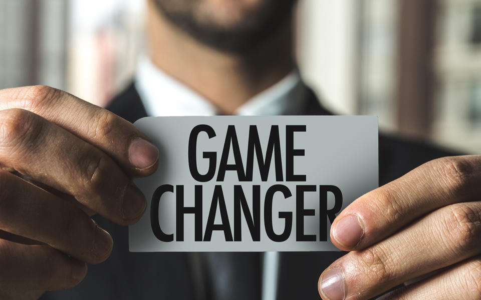 Business person holding card that says game changer.