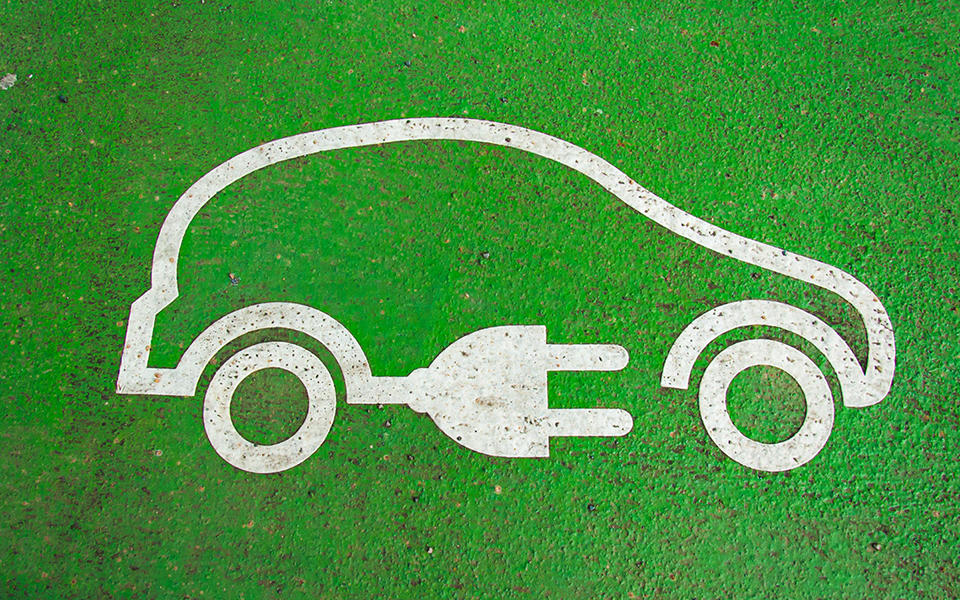 electric vehicle symbol of a car with a plug attached on a green background