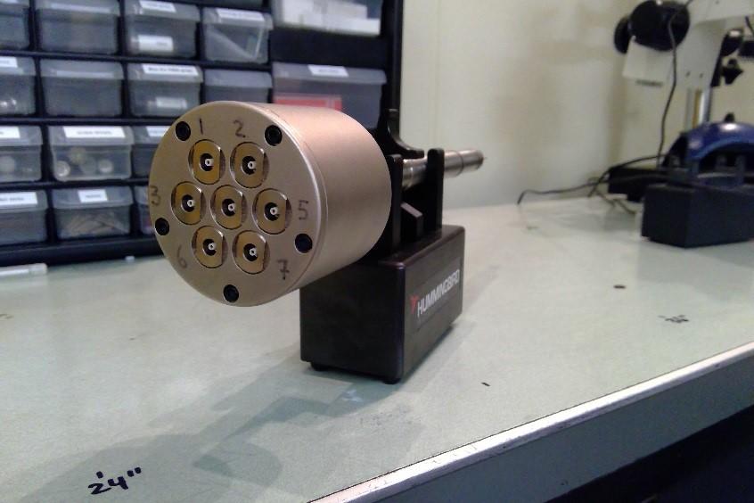 Bronze metal cylinder clamped sideways on a lab bench.