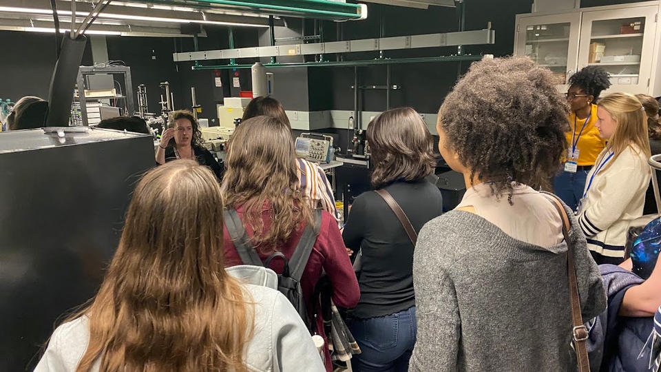 Amber McCreary giving a presentation in a lab to a group of female CUWiP attendees. 