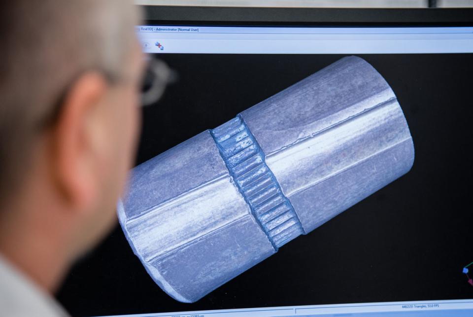 a man looking at a computer screen with a large image of one of the scanned Kennedy bullets