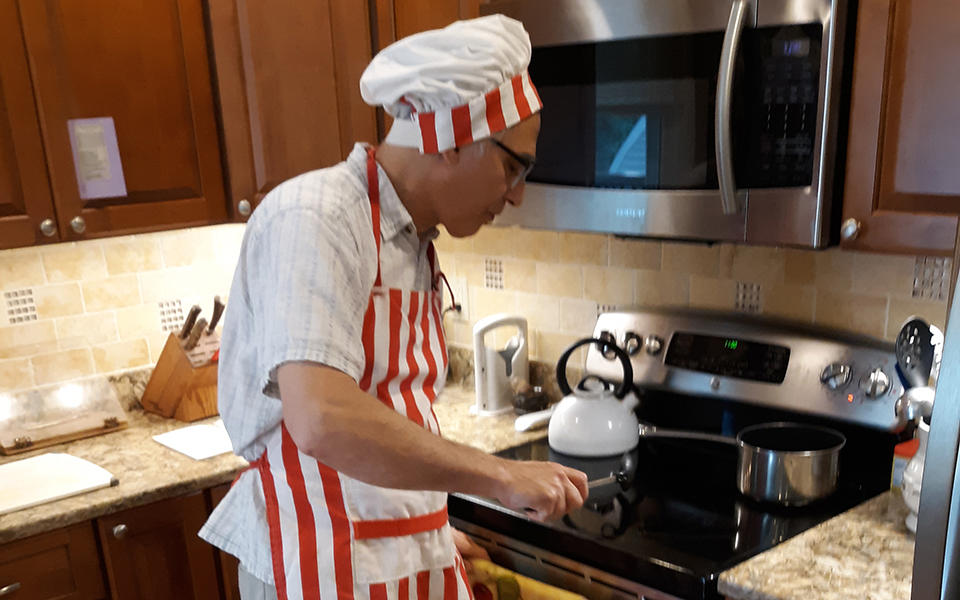 Zach Levine in his kitchen wearing an orange and white striped apron and chef's hat