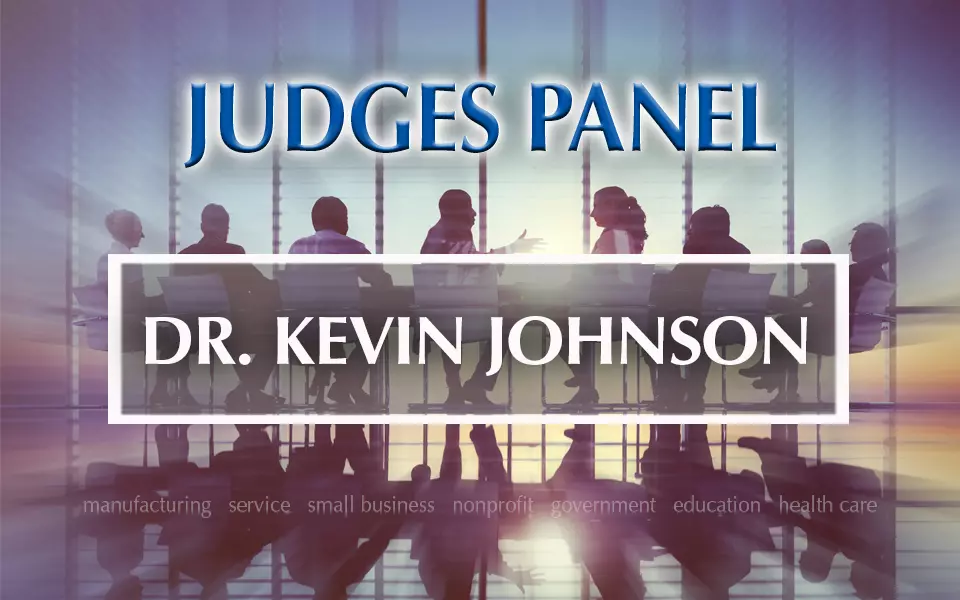 Baldrige Judges Panel Dr. Kevin Johnson with a background panel of people having a discussion.