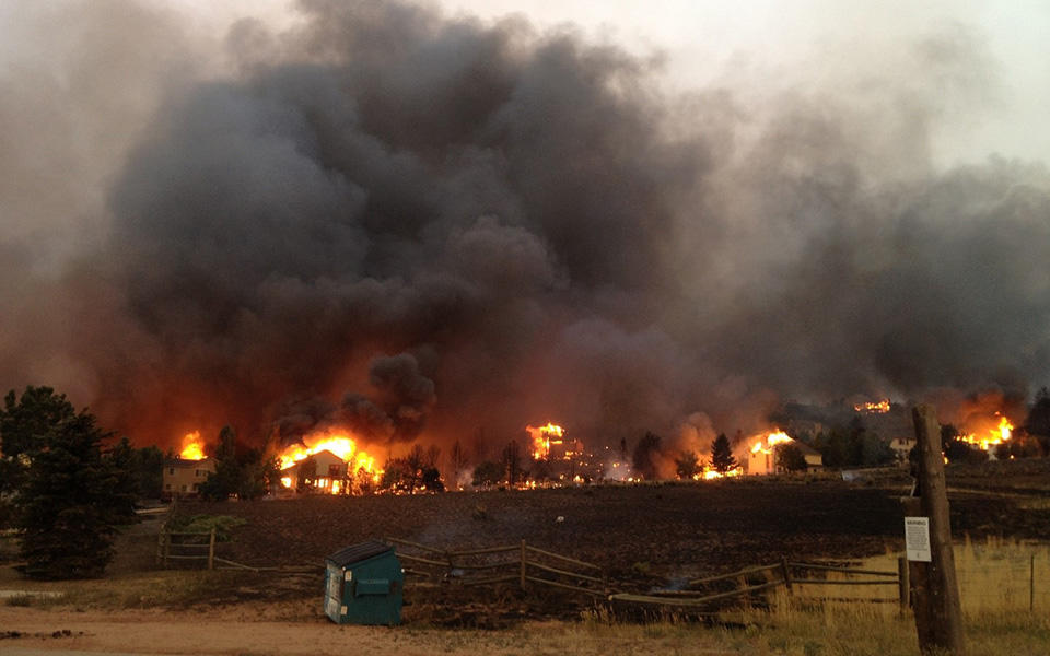 partially knocked down fence in the foreground, a wildfire in the background