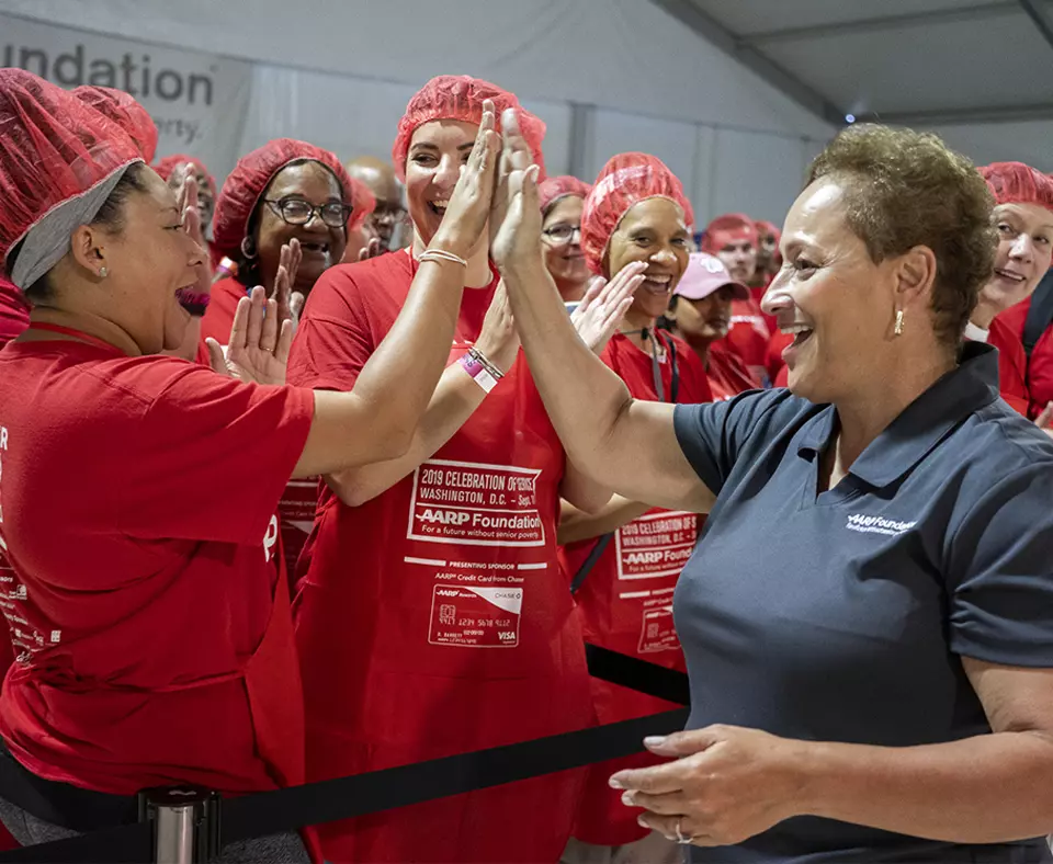 Jo Ann Jenkins, AARP CEO, high-fives a group of volunteers at AARP and the AARP Foundation’s fifth annual “Celebration of Service D.C. Meal Pack Challenge” on Sept. 11, 2019.