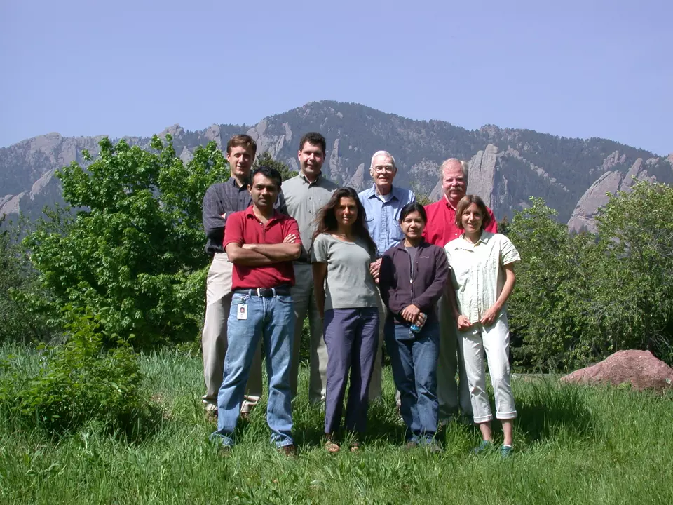 People pose outside with mountains in the background.