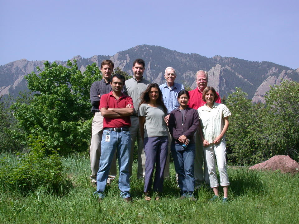 People pose outside with mountains in the background.