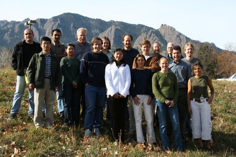 People pose outdoors with mountains in the background.