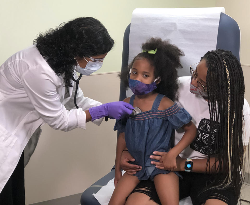 GMBC HealthCare System 2020 Baldrige Award Recipient in Health Care doctor listening to a toddlers heart that is sitting on her mother's lap.