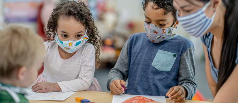 Group of children colouring while wearing masks