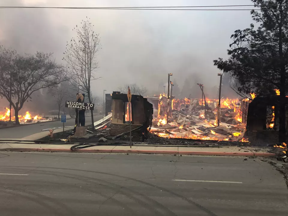 A sign saying "Welcome to Paradise" stands next to a burning building.