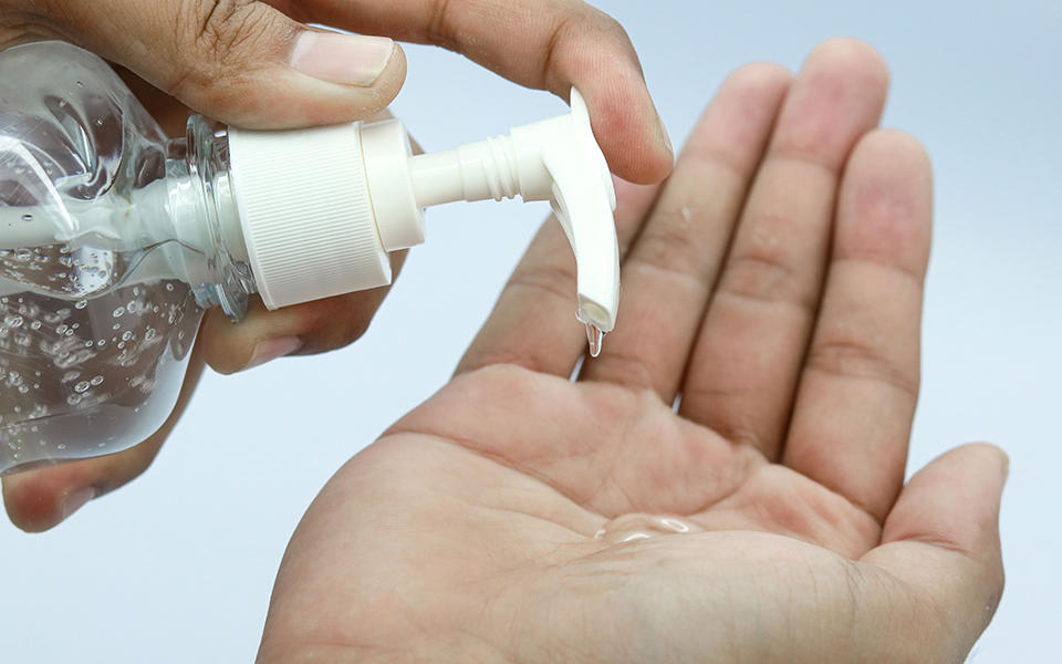 a person dispensing hand sanitizer into their hand