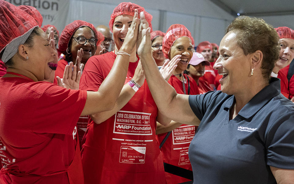 Jo Ann Jenkins, AARP CEO, high-fives a group of volunteers at AARP and the AARP Foundation’s fifth annual “Celebration of Service D.C. Meal Pack Challenge” on Sept. 11, 2019.