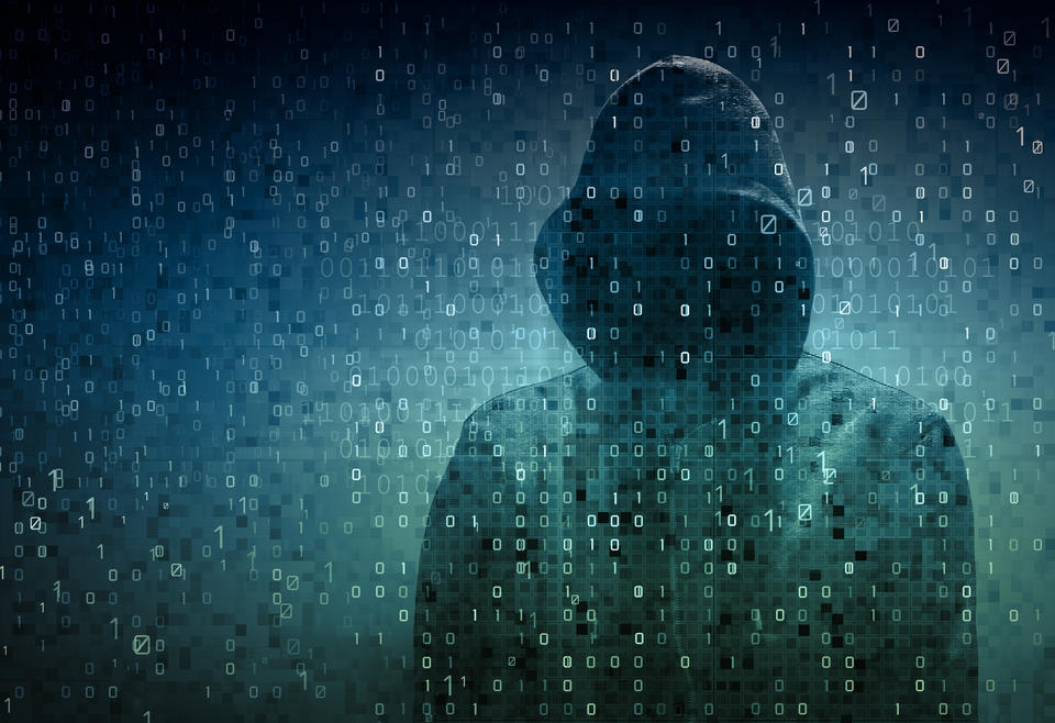 Image of a hacker - dark image of a person behind a wall of code