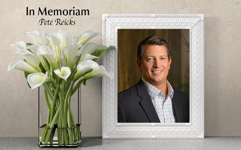 In Memoriam: Photo of Pete Reicks with white lilies in a vase beside frame.