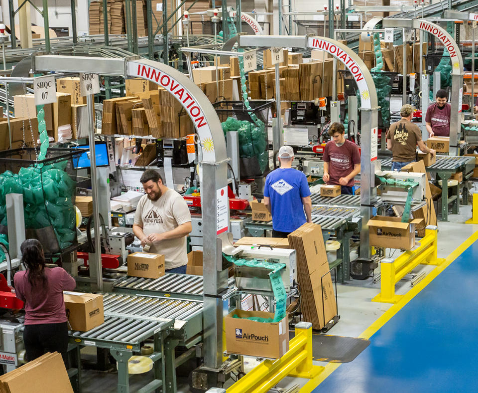 MidwayUSA employees assembling orders in boxes to ship to customers.