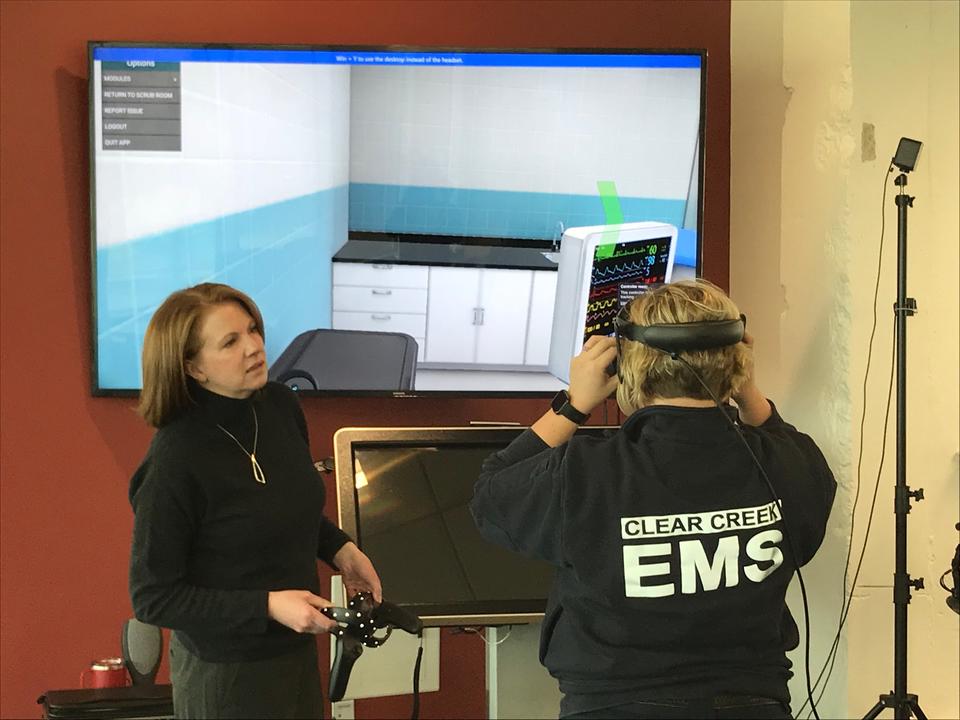 Two women, one of whom is an emergency medical services representative, stand with augmented reality headsets on.