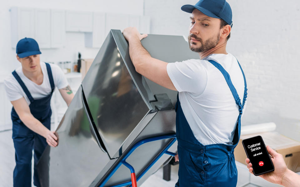 Upset delivery man moving a refrigerator looking at the customer holding the phone that says customer service call ended.