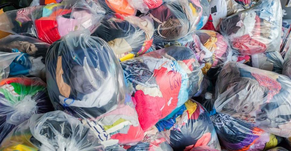 Donated clothes in see-through plastic bags are piled up
