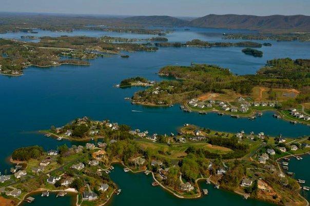 An aerial view of a lake shows homes built along its winding shores.