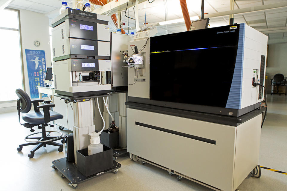 Photograph of a laboratory instrument consisting of a large component on a mobile bench (the mass spectrometer), and a smaller component with stacked modules (the liquid chromatograph).