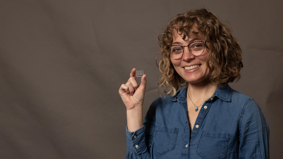 Aly Artusio-Glimpse smiles and holds up a tiny glass square.