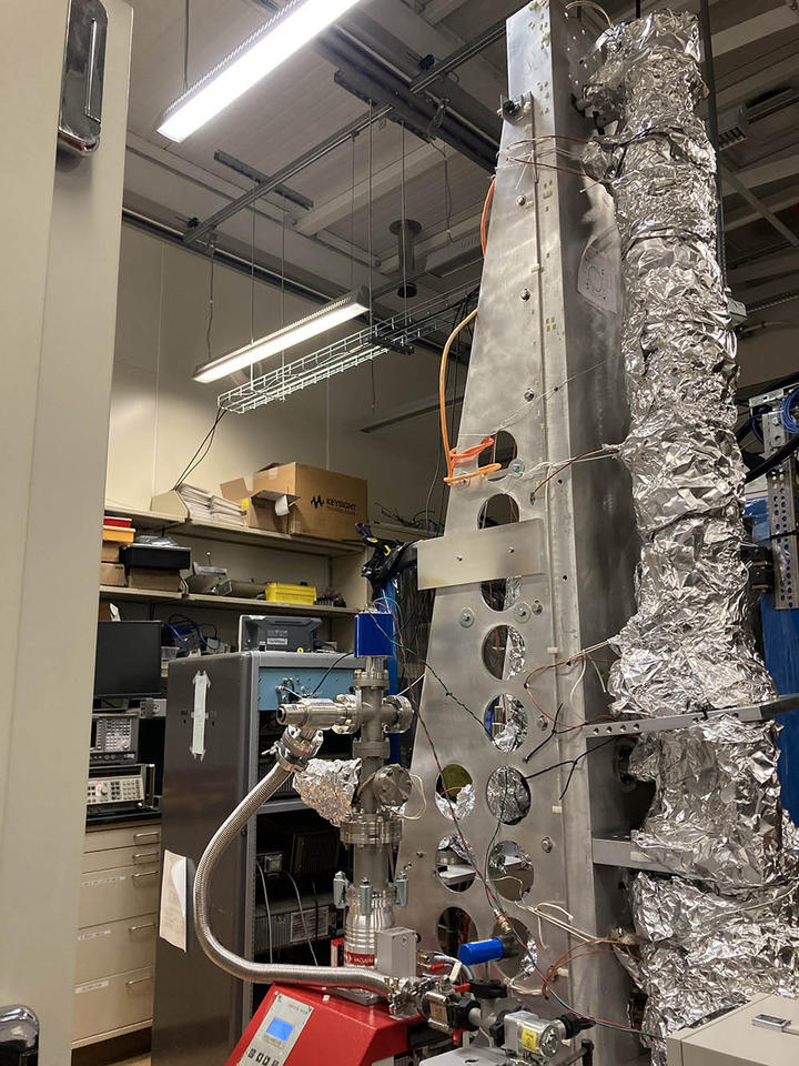 Large scientific device in lab has tall cylindrical portion wrapped in aluminum foil.