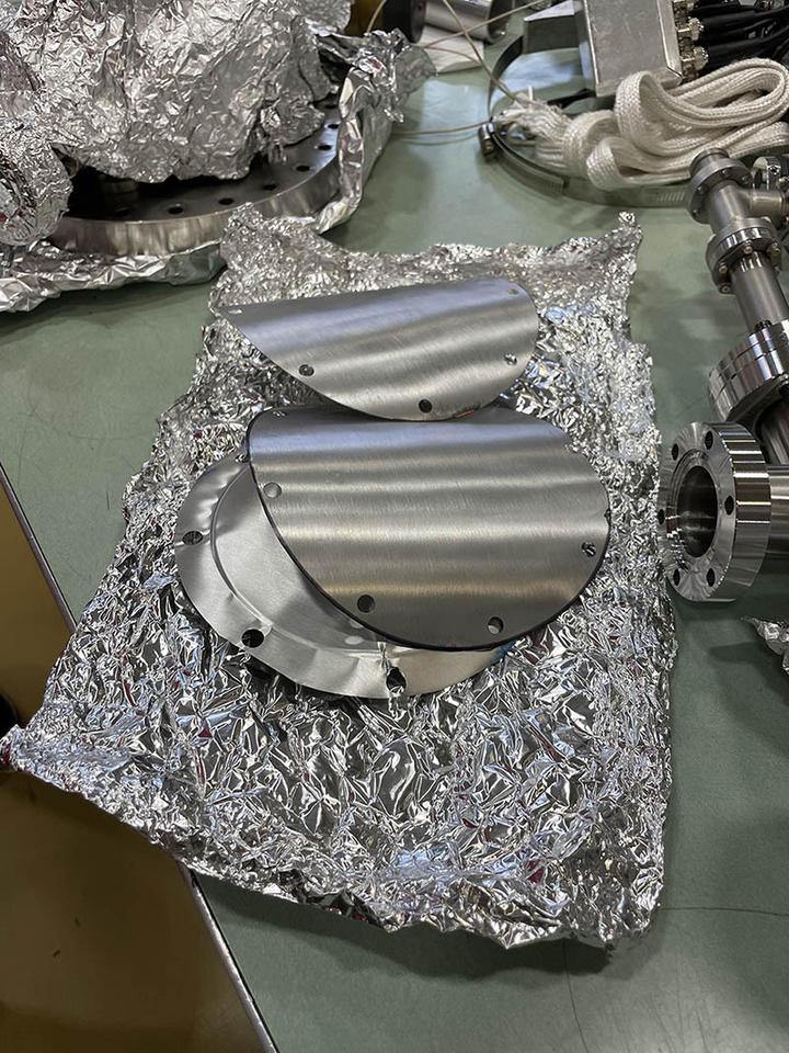 Disk-shaped pieces of aluminum are scattered on a lab table along with aluminum foil.