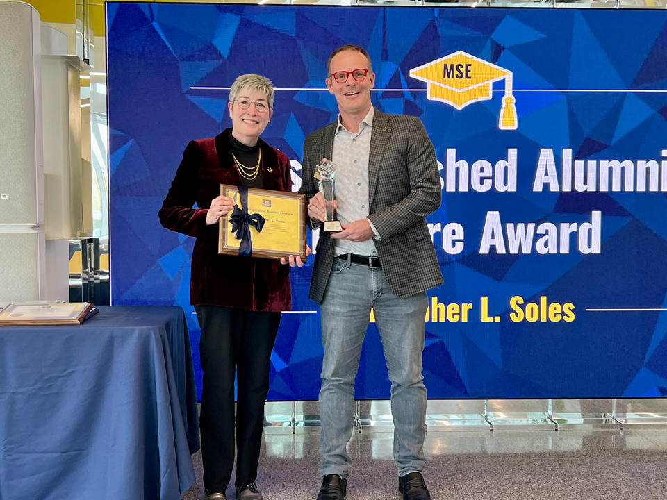 Two people posing with an award