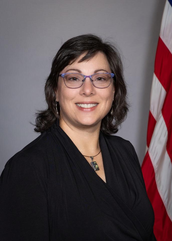 Studio head shot of Rachel Glenn with U.S. flag in background