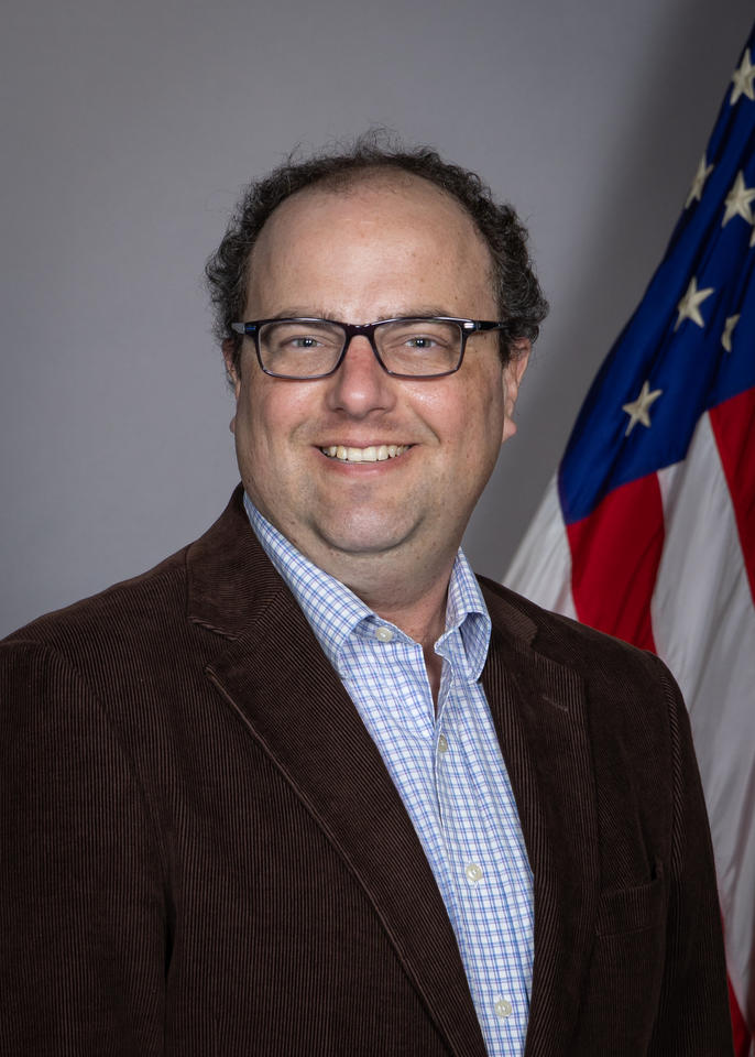 Jeremy Lawson poses for a head shot with an American flag in the background.