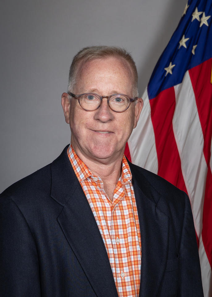 James Schufreider poses for a head shot with an American flag in the background.