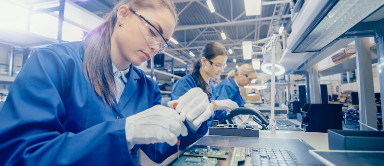 emale Electronics Factory Worker in Blue Work Coat and Protective Glasses