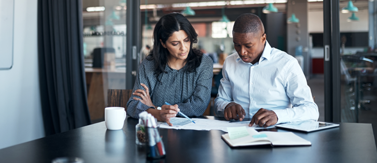 Businessman and businesswoman going over paperwork in a modern office