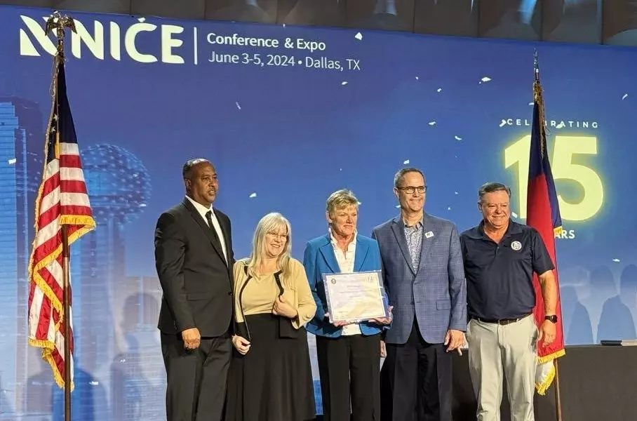 People on stage at the NICE conference standing between an American flag and Texas flag