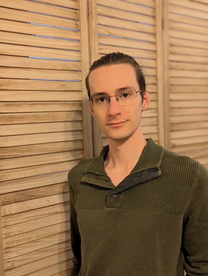 Man standing near bifold doors wearing a green collared shirt and glassese