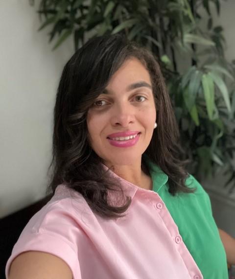 woman with dark hair wearing a pink and green top