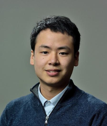 portrait of a man with dark hair wearing a blue shirt