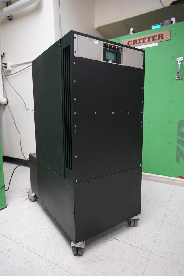 A rectangular black cabinet on wheels has a few switches and a small screen near the top. 