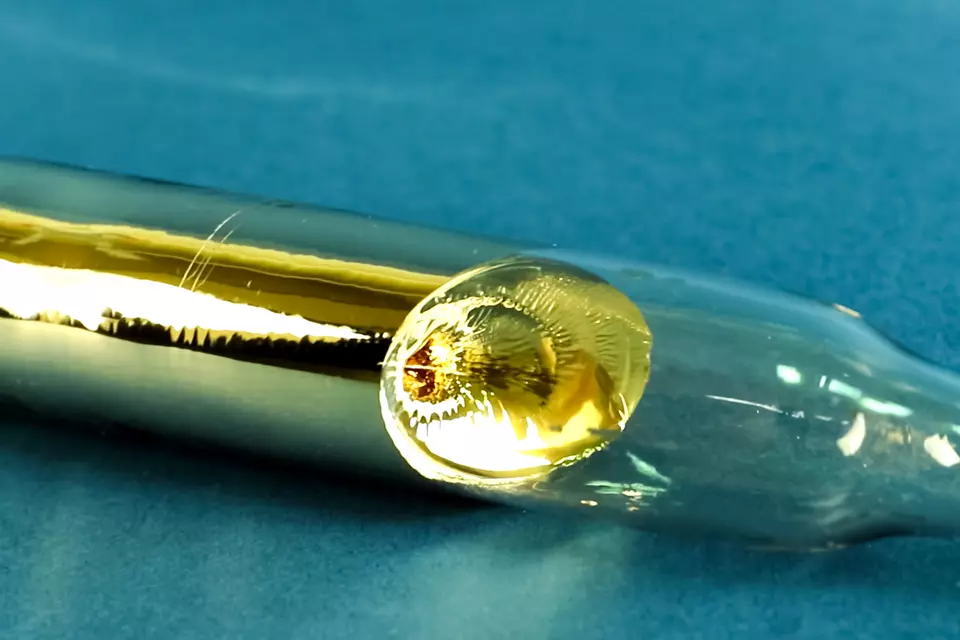 Gold-colored metal fills part of a glass tube. 